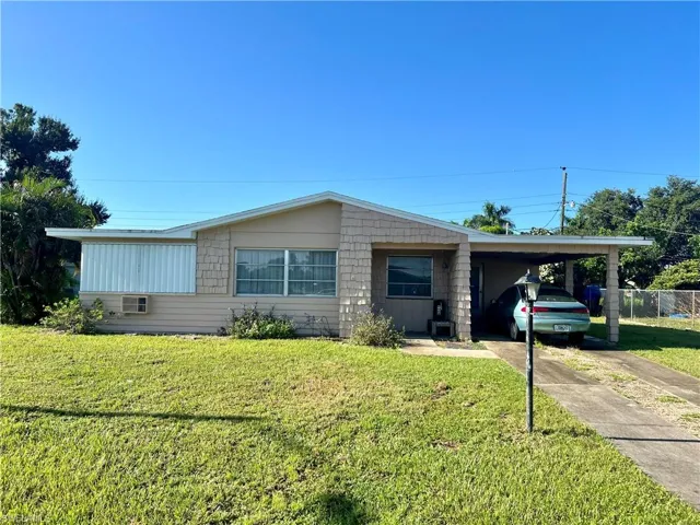View of front facade featuring a carport and a front yard