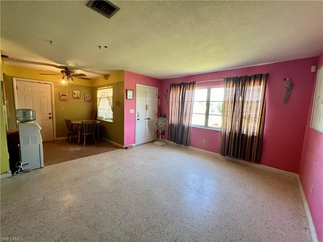 Unfurnished living room featuring a textured ceiling and ceiling fan