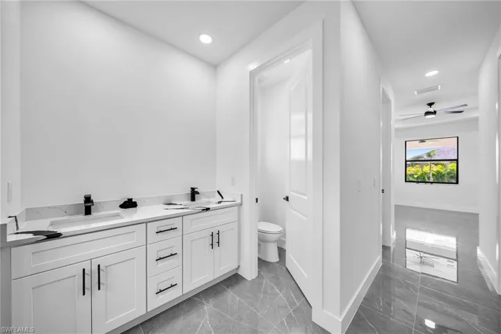 Bathroom with vanity, toilet, and ceiling fan