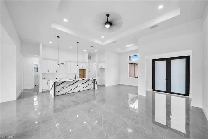 Living room with a raised ceiling, sink, and ceiling fan