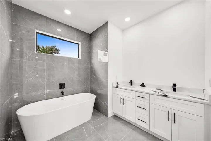 Bathroom with vanity, tile walls, and a bathtub