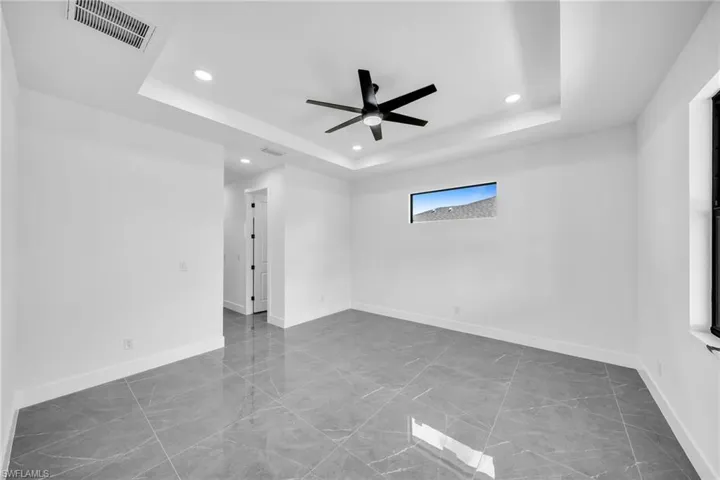 Unfurnished room featuring a raised ceiling and ceiling fan