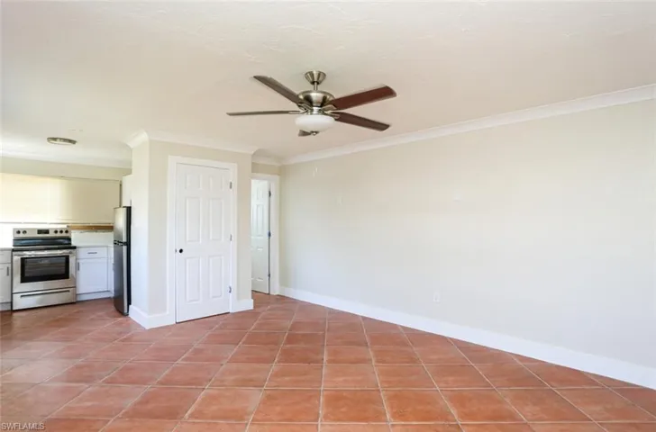 Tiled empty room featuring crown molding and ceiling fan