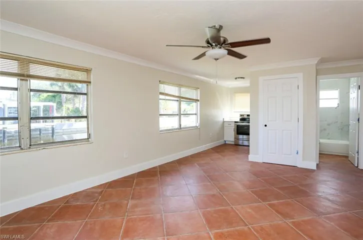 Tiled spare room featuring crown molding and ceiling fan
