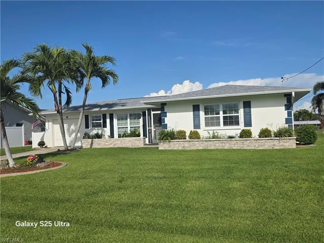 Single story home with stucco siding, an attached garage, fence, and a front lawn