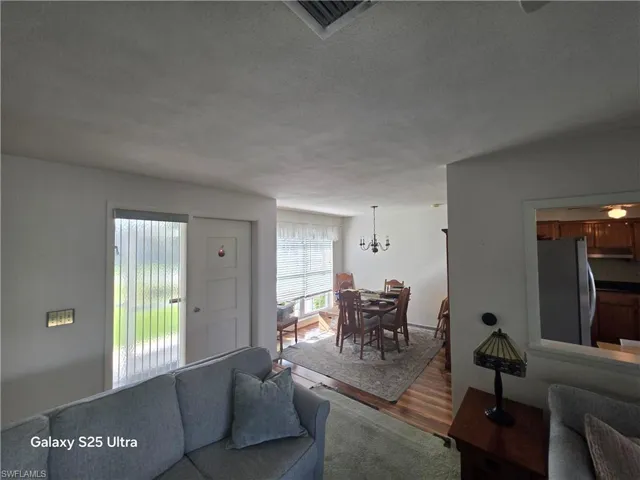 Living area featuring a textured ceiling, wood finished floors, and a chandelier