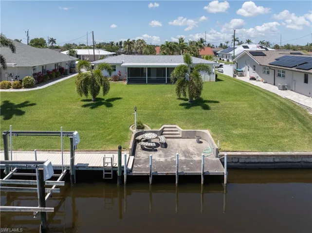 View of dock with boat lift, a yard, and a water view
