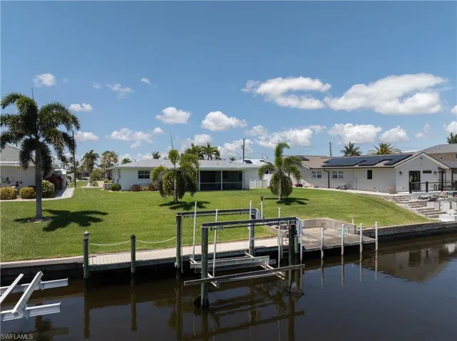 Dock area featuring boat lift, a yard, a residential view, and a water view