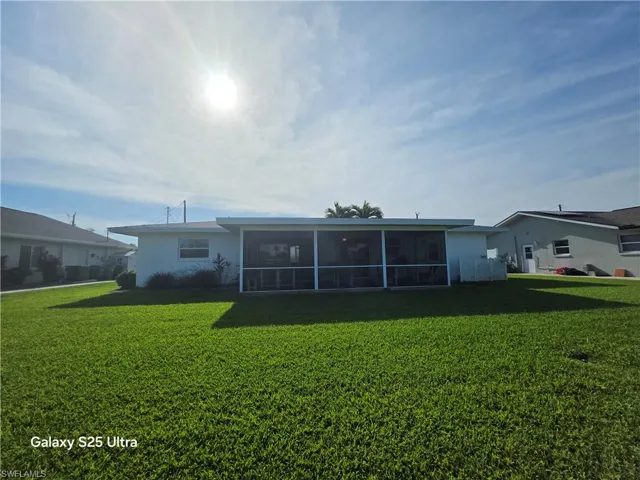 Rear view of property with a lawn and a sunroom