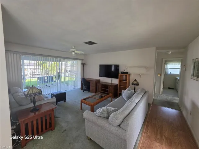 Living room featuring visible vents, wood finished floors, and ceiling fan