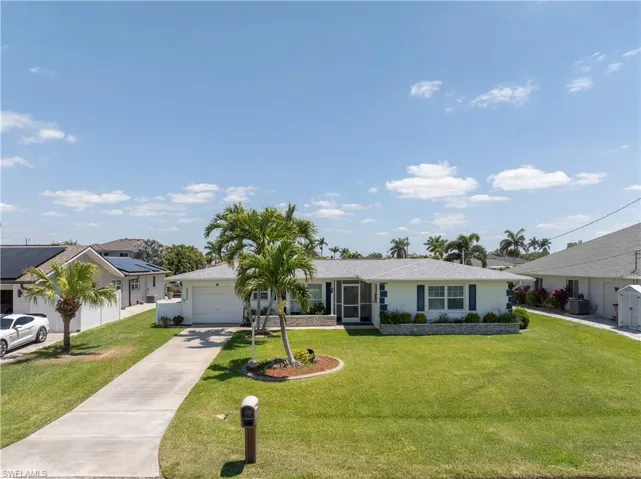 Ranch-style house with an attached garage, driveway, and a front lawn