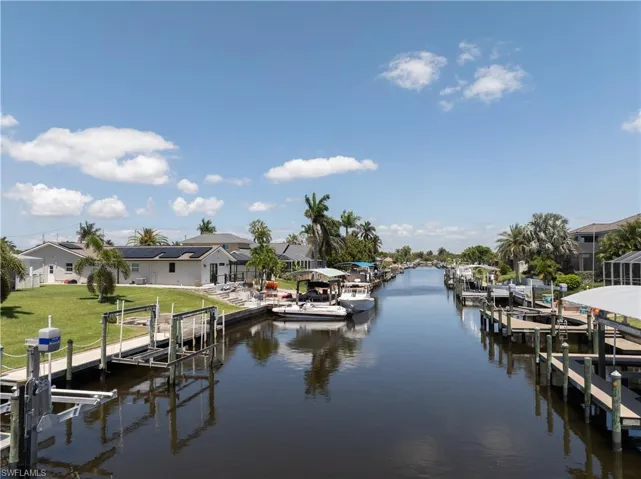 View of dock with boat lift, a residential view, a water view, and a lawn