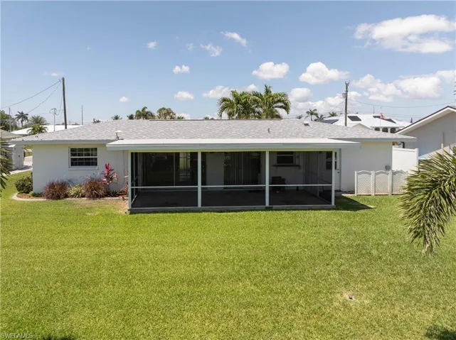 Rear view of property with a sunroom, a yard, stucco siding, and fence