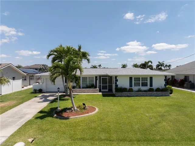 Ranch-style home featuring a garage, a front yard, driveway, and fence