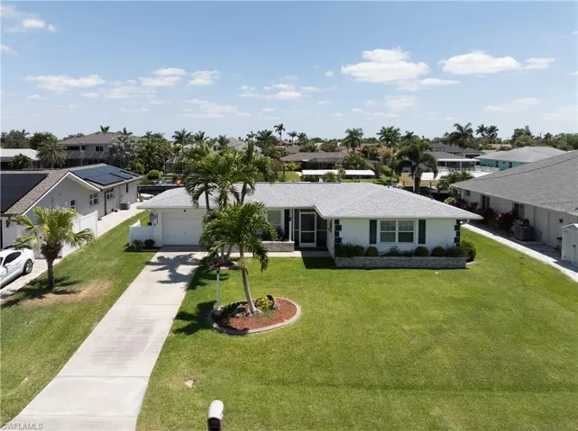 Ranch-style house with stucco siding, a front lawn, an attached garage, concrete driveway, and a residential view