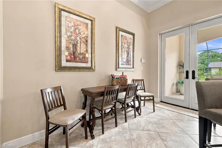 Neutral-toned interior space featuring light tile flooring set on a diagonal, crown molding, and double glass-pane doors leading to an enclosed outdoor area