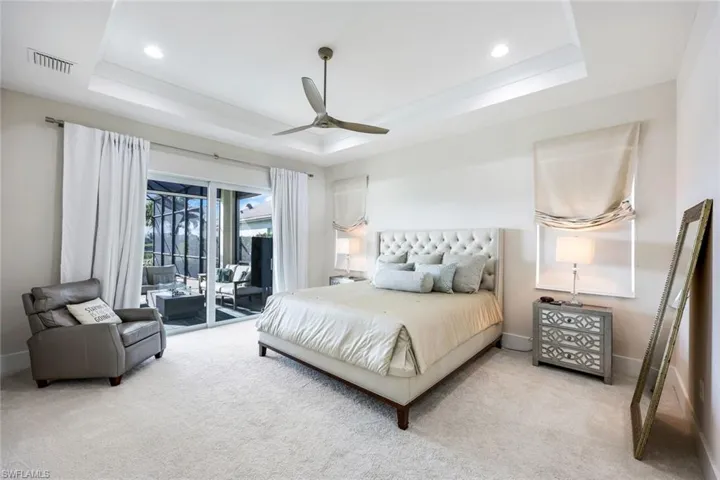 Carpeted bedroom featuring a raised ceiling, access to exterior, and ceiling fan
