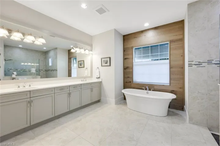 Bathroom featuring shower with separate bathtub and vanity