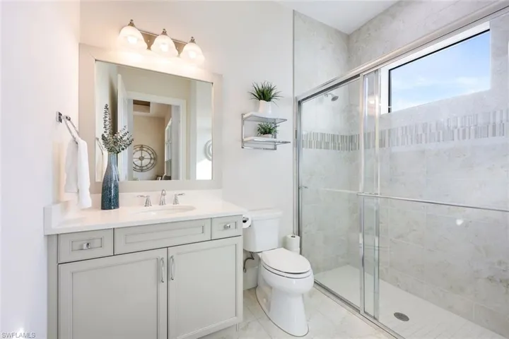 Bathroom featuring vanity, toilet, and a shower with door