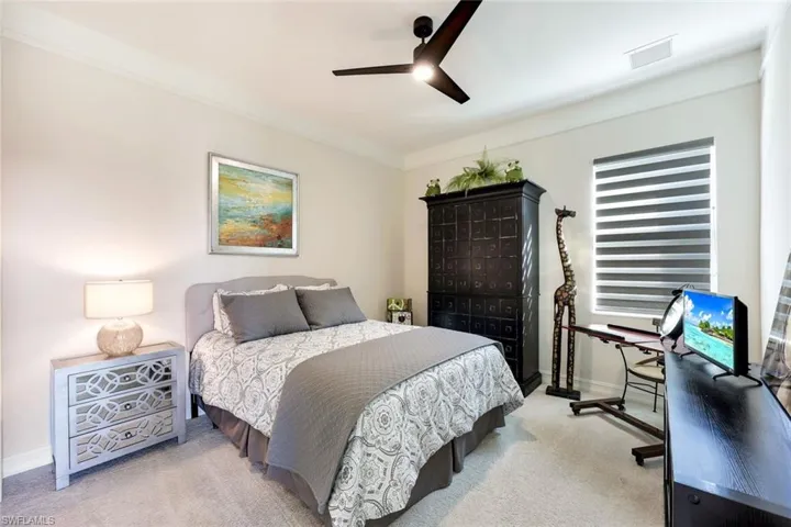 Carpeted bedroom with ceiling fan and ornamental molding