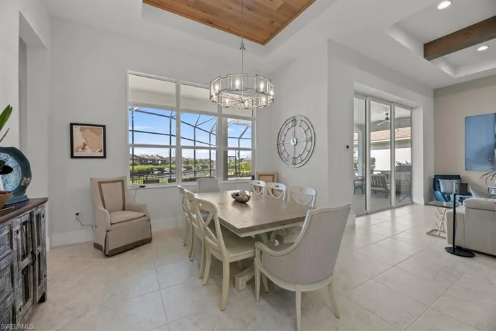 Dining space with a raised ceiling, wooden ceiling, light tile patterned floors, and an inviting chandelier