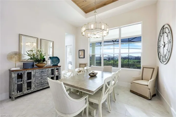 Dining room with a tray ceiling, wooden ceiling, and a notable chandelier
