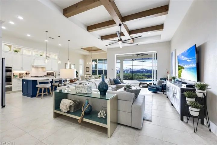 Living room featuring ceiling fan with notable chandelier, beam ceiling, and coffered ceiling