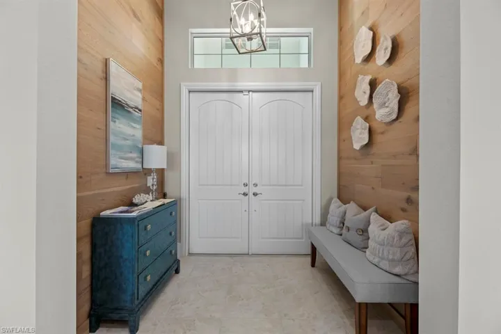 Entrance foyer with wood walls, a towering ceiling, and a chandelier
