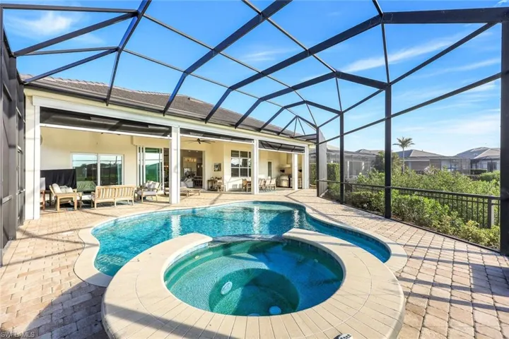 View of pool featuring glass enclosure, ceiling fan, an outdoor living space, a patio area, and an in ground hot tub