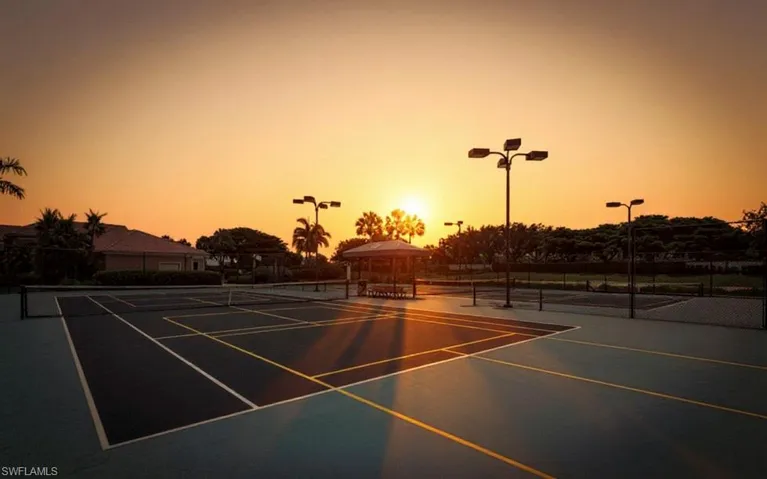 Outdoor tennis courts featuring hard surfaces, perimeter fencing, and integrated lighting fixtures