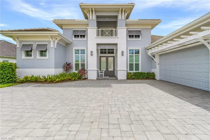 View of front of home featuring stucco siding, decorative driveway, and a balcony