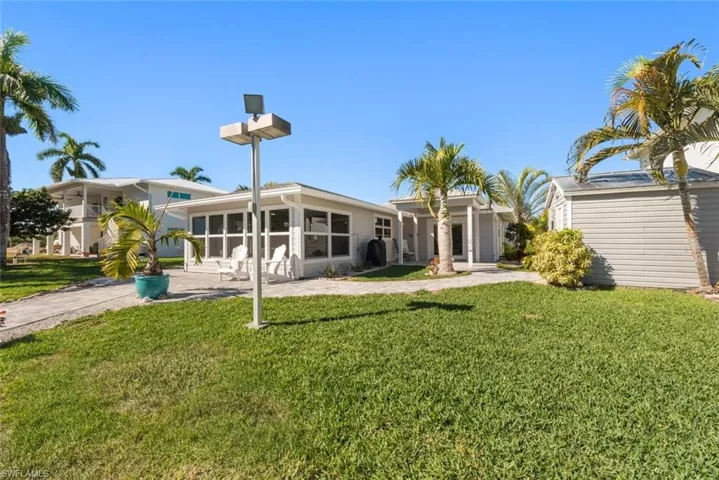 Rear view of house with a lawn, a sunroom, and a patio
