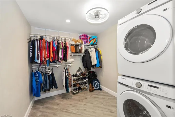 Laundry area featuring stacked washer and dryer, light wood-style floors, and recessed lighting