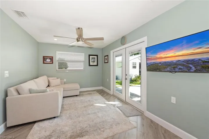 Living area featuring healthy amount of natural light, french doors, ceiling fan, and light wood-style flooring