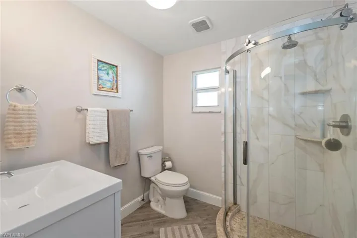 Bathroom featuring vanity, a marble finish shower, and light wood-type flooring