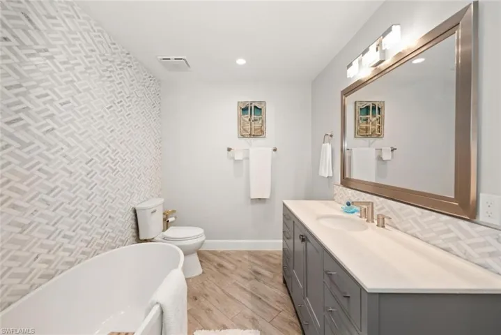 Bathroom with a soaking tub, vanity, light wood finished floors, and recessed lighting