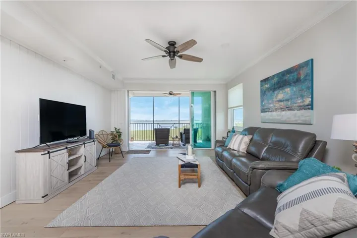 Living room featuring ornamental molding, ceiling fan, and light wood-type flooring