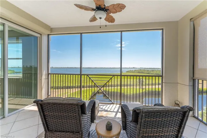 Sunroom with ceiling fan and a water view