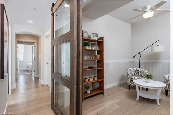 Living area with ceiling fan, a barn door, and light hardwood / wood-style flooring