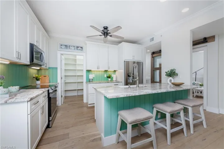 Kitchen featuring appliances with stainless steel finishes, light hardwood / wood-style floors, white cabinets, and ceiling fan