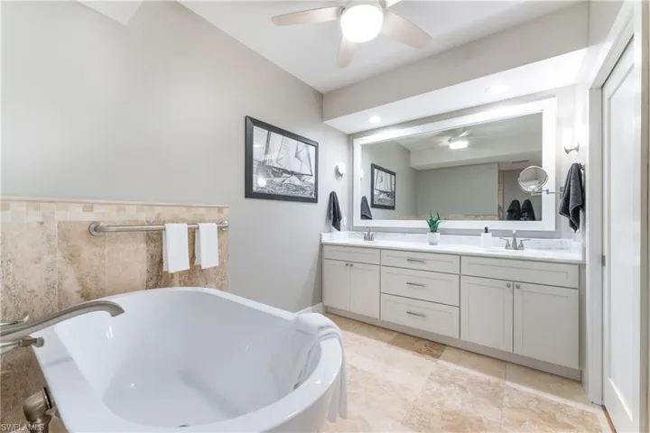 Bathroom featuring dual vanity, ceiling fan, tile floors, and a bathing tub