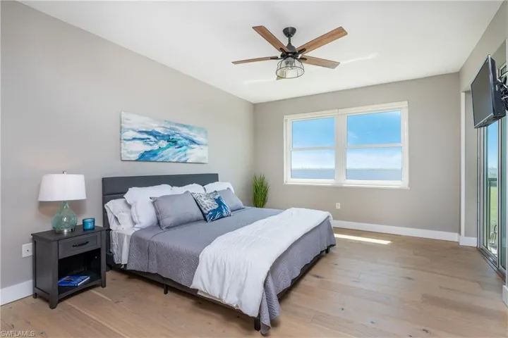 Bedroom featuring ceiling fan, light hardwood / wood-style flooring, and multiple windows