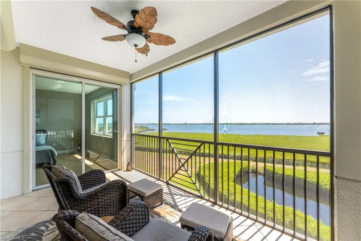Sunroom / solarium featuring ceiling fan and a water view