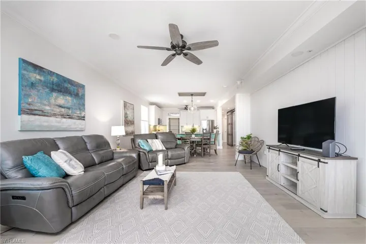 Living room featuring ornamental molding, ceiling fan, and light wood-type flooring