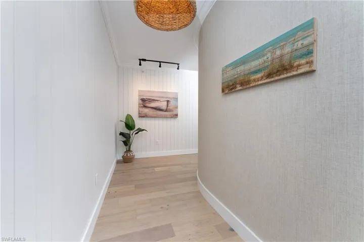 Hall featuring light wood-type flooring, rail lighting, and crown molding
