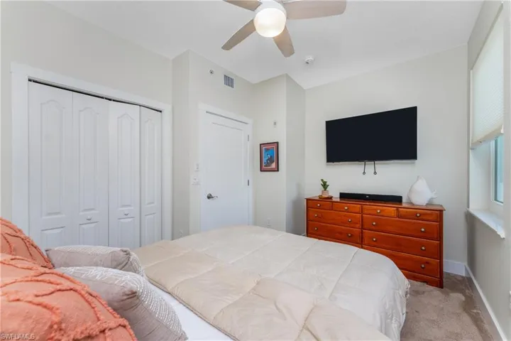 Carpeted bedroom with ceiling fan and a closet