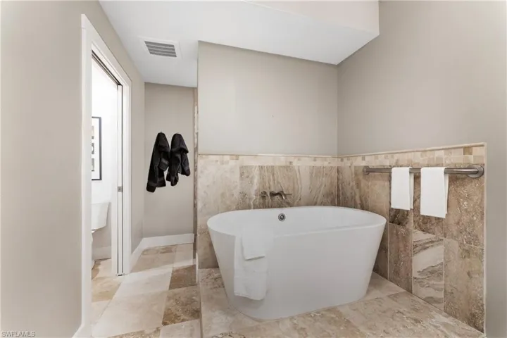 Bathroom with tile flooring, tile walls, toilet, and a bathtub