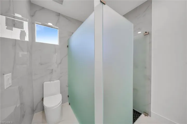 Bathroom featuring an enclosed shower, toilet, and tile patterned floors