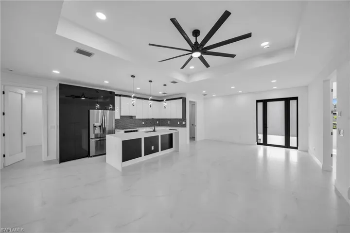 Living room featuring a tray ceiling, ceiling fan, and sink