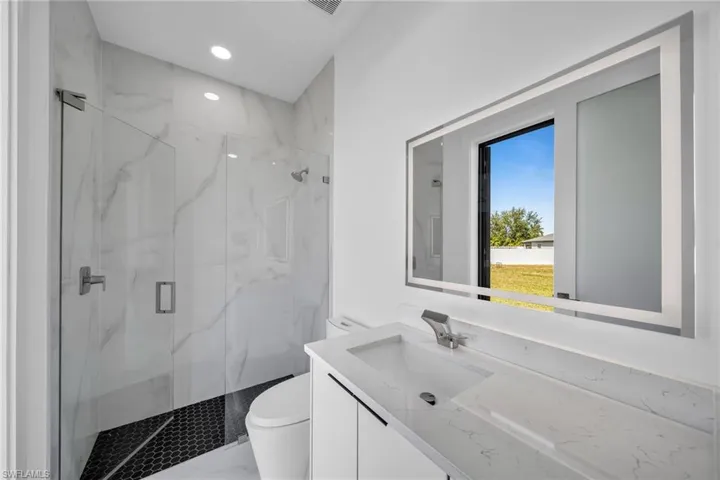 Bathroom with vanity, toilet, and a shower with shower door